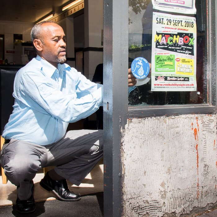 Stapleton Road refill station Man adding a refill station window sticker