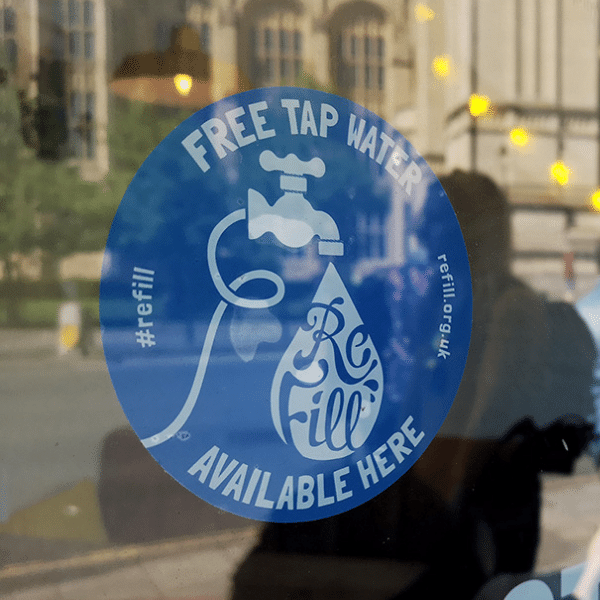 man in bar with Refill sticker and two glasses with a bottle of water